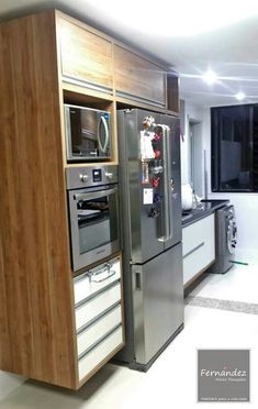 a modern kitchen with stainless steel appliances and wood paneled cabinetry, along with white tile flooring