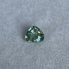 a pear shaped green diamond sitting on top of a gray carpeted floor next to a white wall