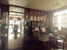 a living room filled with lots of furniture next to a chandelier and windows