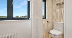 a white toilet sitting next to a window in a bathroom near a radiator