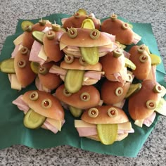 a pile of hotdogs with pickles and cheese on them sitting on top of a green napkin