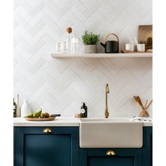 a kitchen with blue cabinets and white tile backsplashing, gold faucets