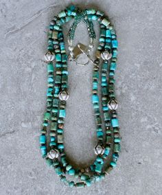 This good-looking Necklace showcases 3 strands of Mixed Turquoise, including 6-by-9mm Drum Beads, 4-by-6mm Rondelles, 6mm Triangles and 4mm Heishi. The Turquoise displays a variety of blue and green hues, creating a color palate that is visually engaging. It is paired with several other complementary elements, notable of which are the 11-by-12mm Hill Tribe Silver Ridged Bicones. The Bicones are beautifully crafted and polished to a soft luster. Other elements are comprised of: 6mm green Rutilate Elegant Multi-strand Turquoise Gemstone Necklace, Turquoise Multi-strand Hand-strung Jewelry, Unique Multi-strand Turquoise Jewelry, Unique Turquoise Multi-strand Jewelry, Turquoise Multi-strand Jewelry For Jewelry Making, Multi-strand Turquoise Gemstone Beads Necklace For Jewelry Making, Multi-strand Turquoise Necklace For Jewelry Making, Artisan Multi-strand Jewelry With Spacer Beads, Handmade Double Strand Turquoise Jewelry