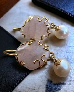 These elegant earrings are made of gold-plated 925 silver and feature a sophisticated design. Each earring is adorned with a large rose quartz, a translucent pink semi-precious stone, set with a decorative gold setting. A river pearl hangs beneath the bead, adding a touch of classicism and refinement. The contrast between the pink of the quartz and the shiny white of the pearl, together with the warm golden tone of the frame, creates a fascinating and versatile accessory, perfect to complete any Elegant Rose Quartz Drop Earrings, Elegant Rose Quartz Gemstone Earrings, River Pearls, Jeweled Earrings, Quartz Rose, Elegant Earrings, Wedding Earrings, Semiprecious Stones, Rose Quartz