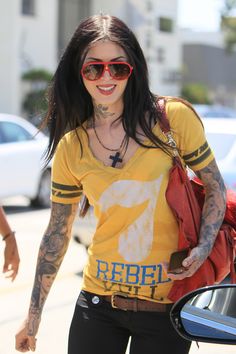 a woman walking down the street with her hand in her pocket and tattoos on her arm