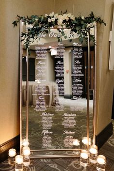 a large mirror with candles on the floor in front of it that has a seating chart