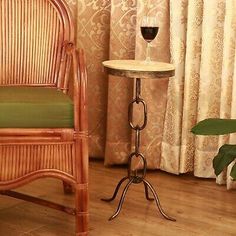 a wicker chair next to a small table with a glass of wine on it