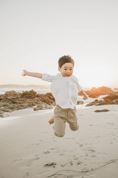 a young boy is jumping in the air at the beach