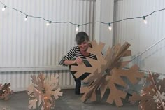 a woman standing next to a snowflake made out of cardboard and string lights