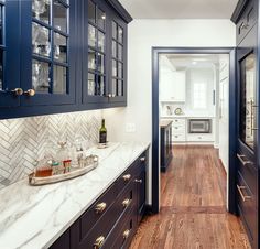 a kitchen with blue cabinets and white counter tops, wood flooring and wooden floors