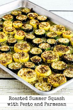 roasted summer squash with pesto and parmesan in a baking dish on a wooden table