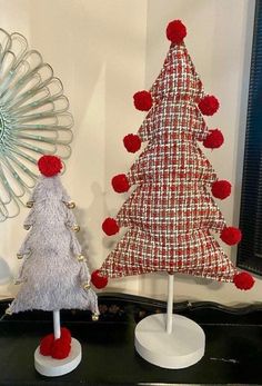 two small christmas trees sitting on top of a table next to a mirror and fan