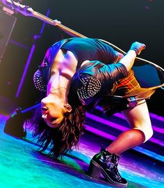 a woman is doing a handstand on stage with her legs in the air