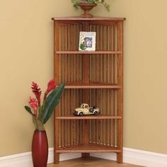 a wooden bookcase sitting on top of a hard wood floor next to a vase with flowers