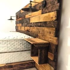 a bed made out of pallet wood with a lamp on the wall above it