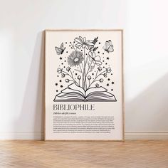 an open book with flowers and butterflies on it, in front of a white wall