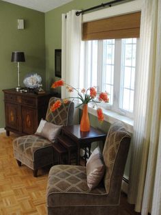 a living room with two chairs and a table in front of a large window filled with flowers