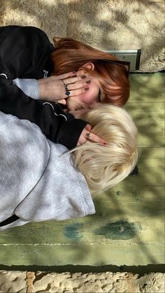 two people are laying on the ground with their heads touching each other's noses