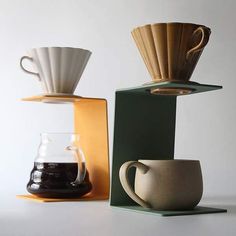 three different coffee cups sitting next to each other on top of a shelf in front of a white wall