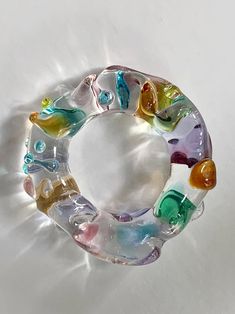 a bracelet made out of glass beads on a white surface with light coming through it