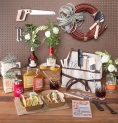 a table topped with bottles of wine and food next to a wreath on the wall