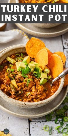 two bowls filled with turkey chili and topped with tortilla chips on the side