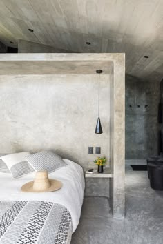 a bedroom with concrete walls and white bedding