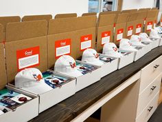 hats are lined up on top of boxes in a row at the end of a table