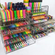 an assortment of pens, markers and pencils in acrylic storage bins