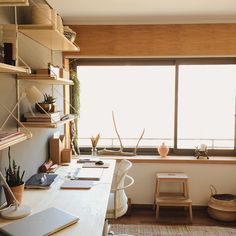 a desk with a laptop on top of it next to a window in a room