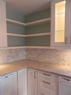 a kitchen with white cabinets and marble counter tops