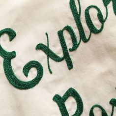 an embroidered t - shirt with the word explore written in green thread on top of it