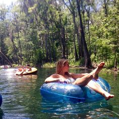 a woman laying on top of an inflatable tube while floating down a river