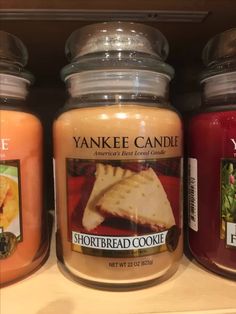 yankee candles are sitting on a shelf in a store, one has a slice of cake and the other is shortbread cookie