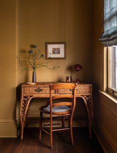 a wooden desk with a chair next to it and a vase on top of it