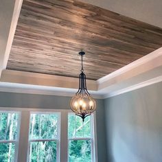 a chandelier hanging from the ceiling in a room with wood paneling and windows