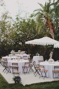 an outdoor dining area with tables, chairs and umbrellas set up for a wedding reception