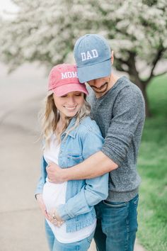 a man and woman hugging each other while standing on the sidewalk in front of trees