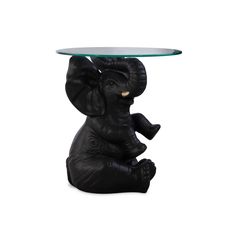 an elephant statue sitting under a glass table