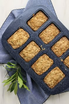 a muffin pan filled with oatmeal squares on top of a blue napkin