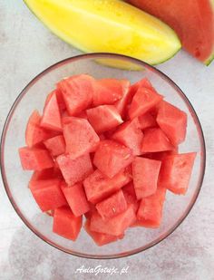 a glass bowl filled with watermelon next to a banana