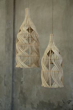 two hanging lights made out of woven material on a concrete wall, one is white and the other is beige