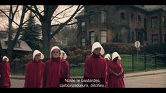 four women in red dresses and white bonnets are walking down the street with trees behind them