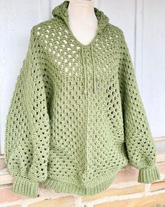 a crocheted green sweater is displayed on a mannequin