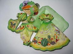 three cloth dolls are sitting next to each other on a white surface, one is green and the other is yellow