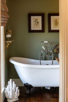 a bathroom with a claw foot tub and pictures on the wall