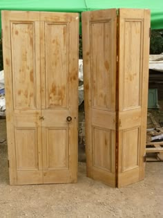 two wooden doors sitting next to each other on the ground in front of a green tarp