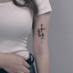 a woman with a cross and roses tattoo on her left arm is shown from the waist up