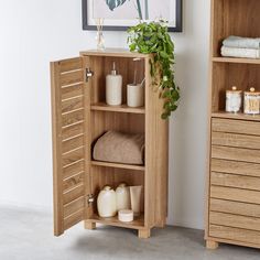 a wooden cabinet with towels and soaps in it next to a plant on the wall