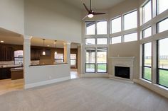 an empty living room with large windows and a fireplace